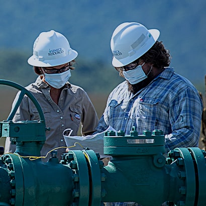 two workers in field reviewing plans