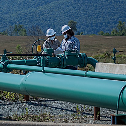 two workers in field reviewing plans