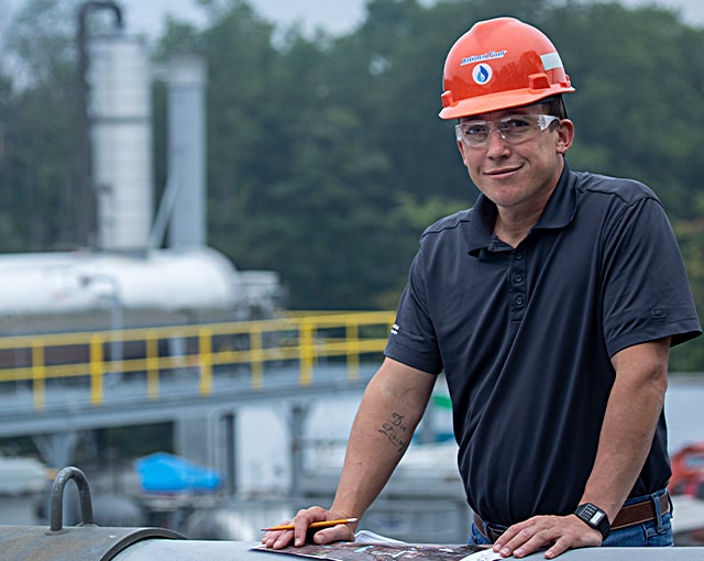 smiling worker in hard hat reviewing plans