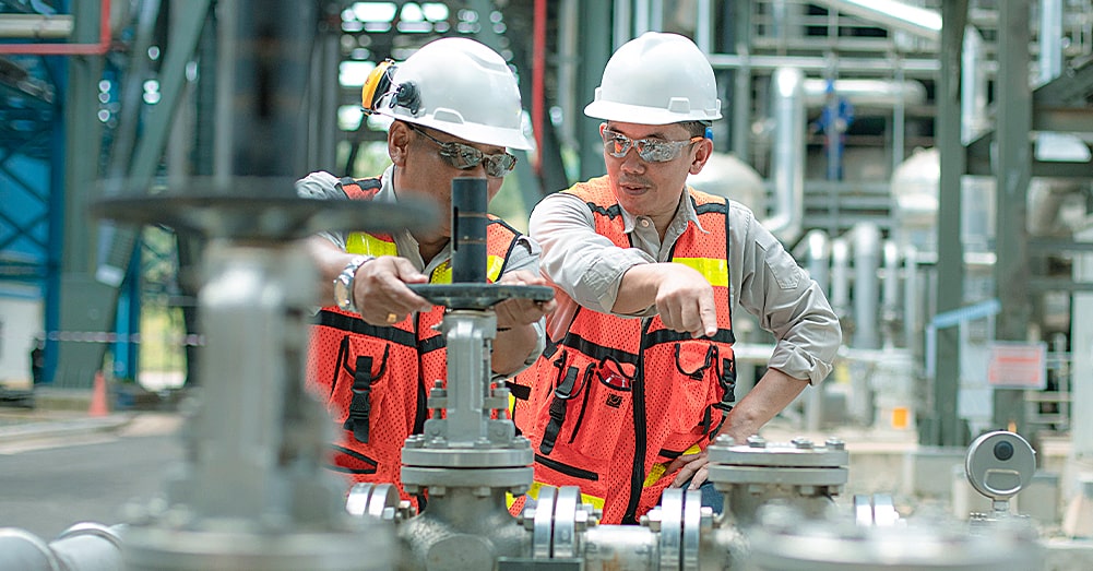 two workers pointing at a machine