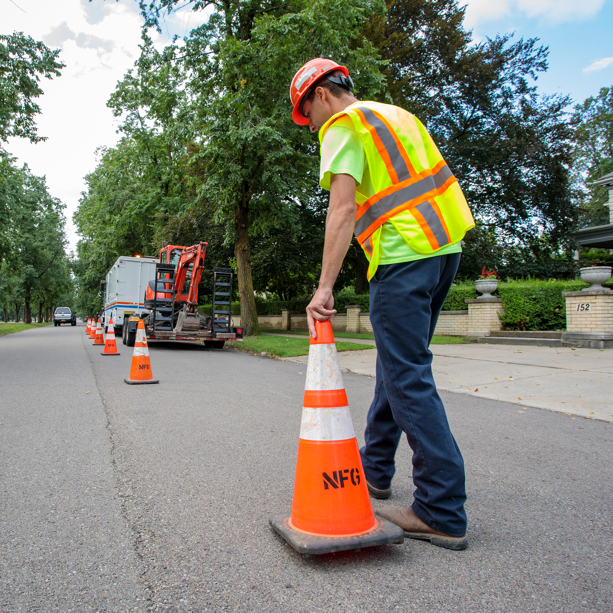 Utility worker in vest putting cones onto street