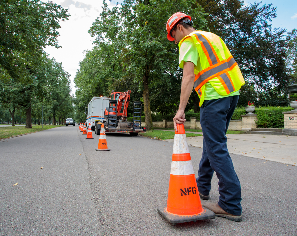 Utility worker in vest putting cones onto street