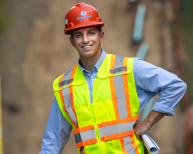 homme souriant dans un casque et un gilet sur un chantier