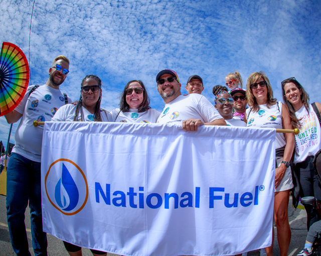 group of employees holding a banner and smiling at the camera