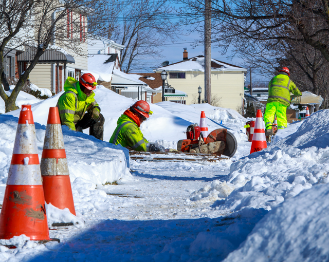 Équipe de services publics travaillant sur un trottoir dans la neige